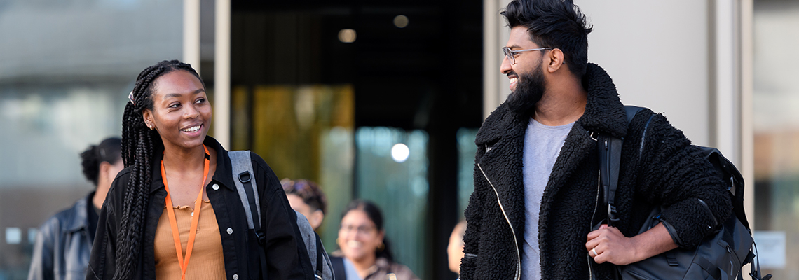 image of students smiling and walking outside of building
