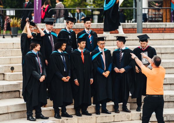 a group of graduates standing on the Piazza stairs, about to have their official group graduation photo taken