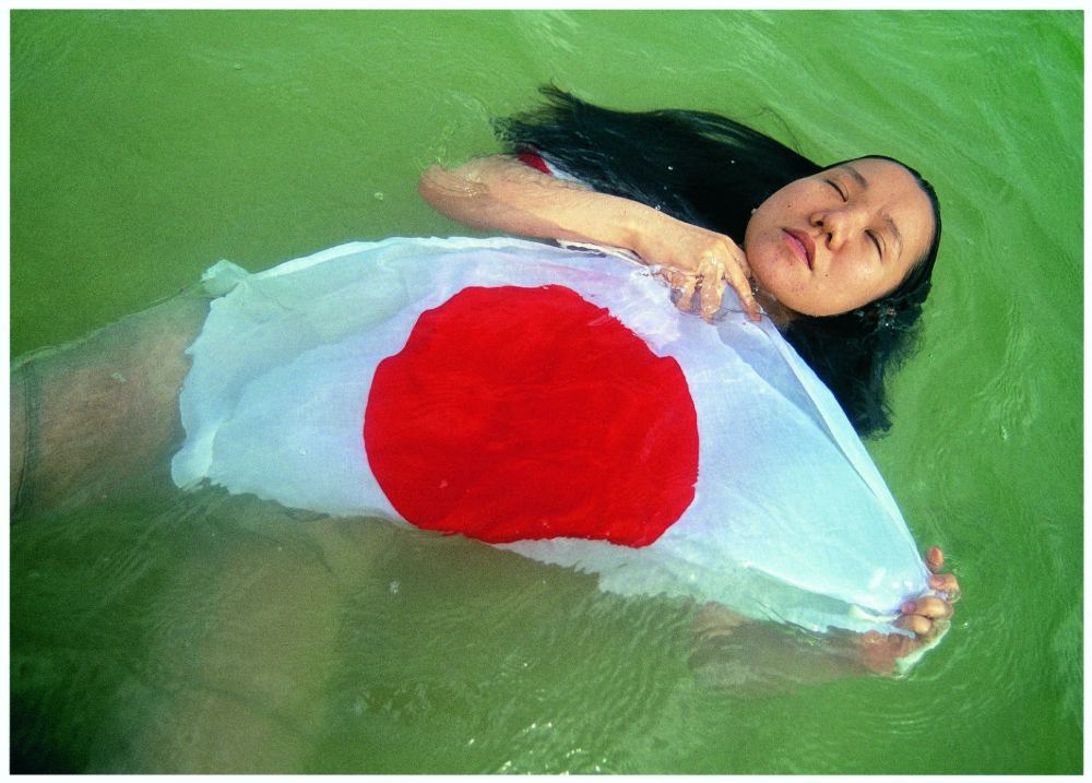 photo from Mao Ishikawa of a woman floating in water holding the Japanese flag