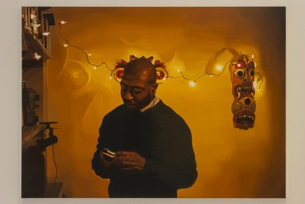 Image of a man stood by a bookcase against a warm gold background with fairy lights 