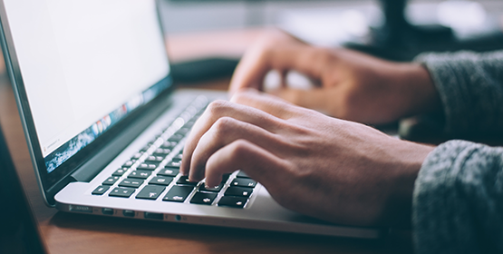 Two hands typing on a laptop keyboard