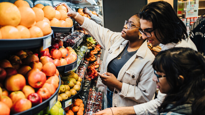 Three people browsing fresh fruit and vegetables in the grocery store