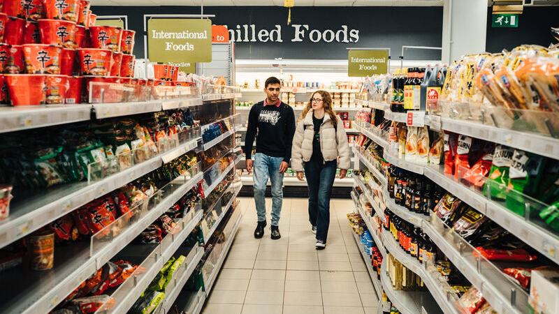 Two students walk down the international food aisle in Rootes grocery store